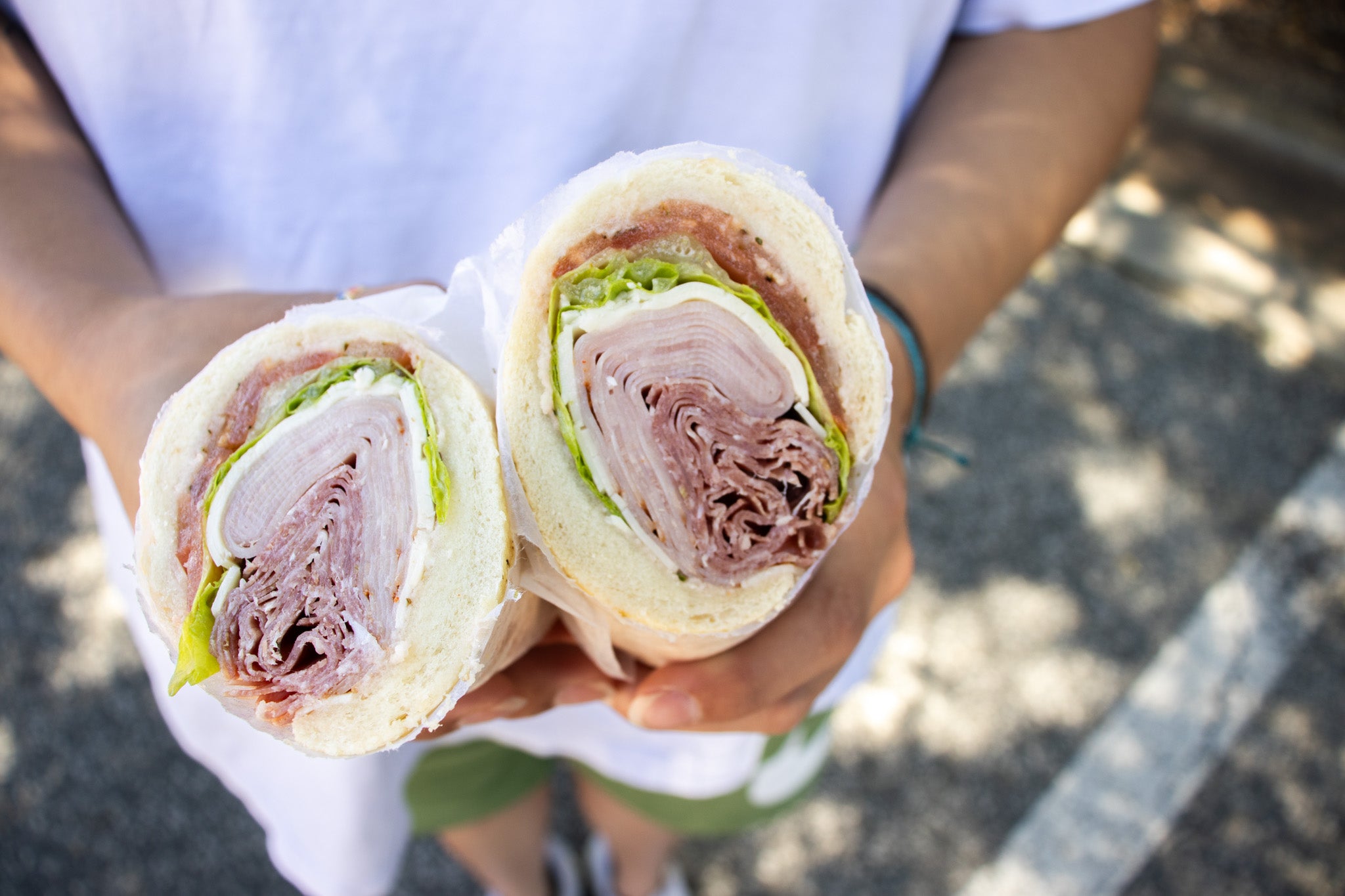 image of hands holding sandwich featuring san giuseppe deli meats 